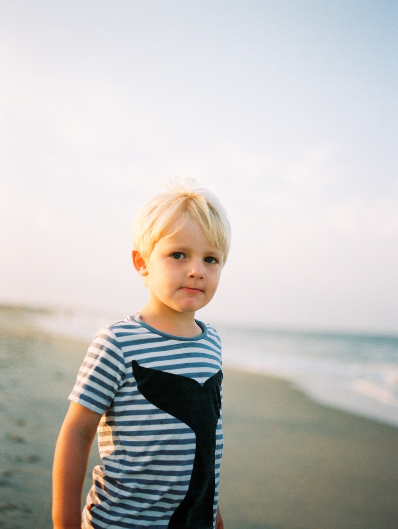 dusk photo of a young blonde boy at the beach
