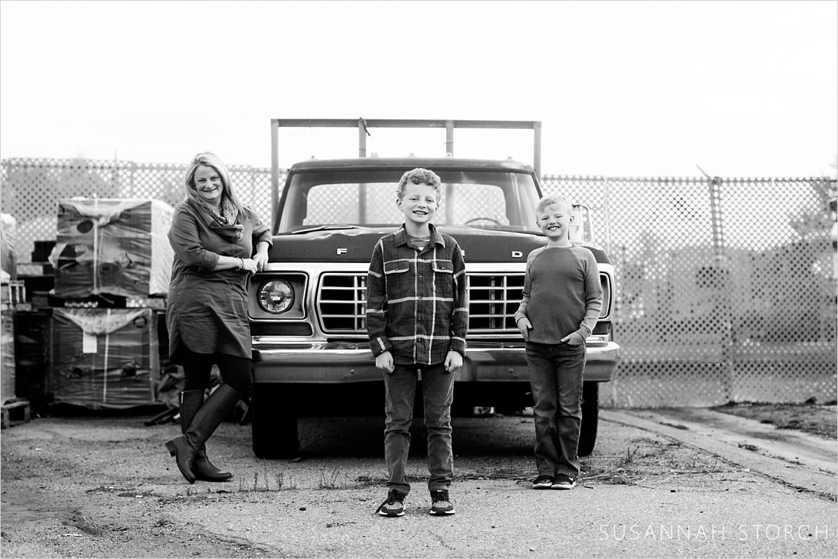 a family stand around an old pick up truck in this black and white photo