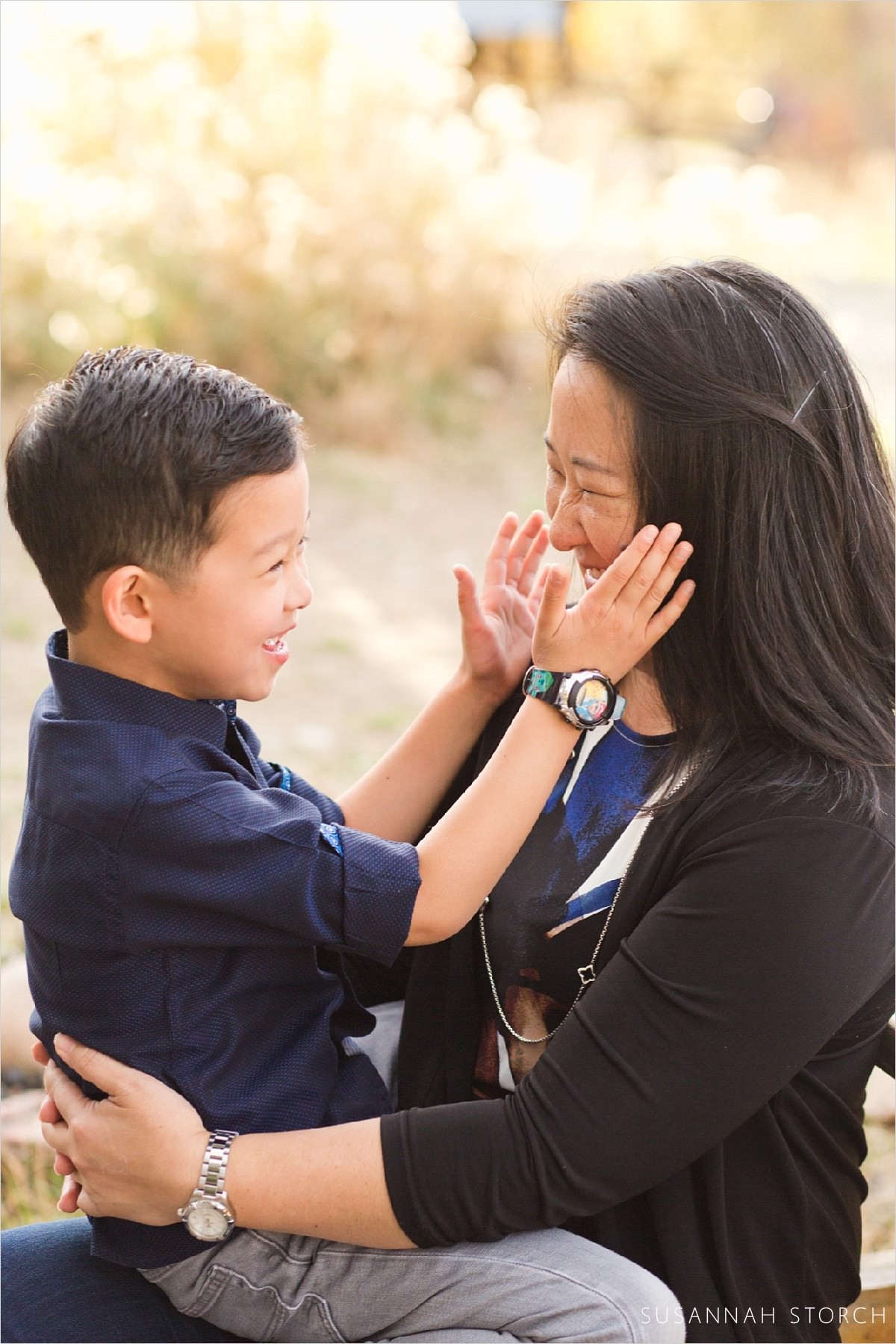 a boy puts his hands on his mom's cheeks