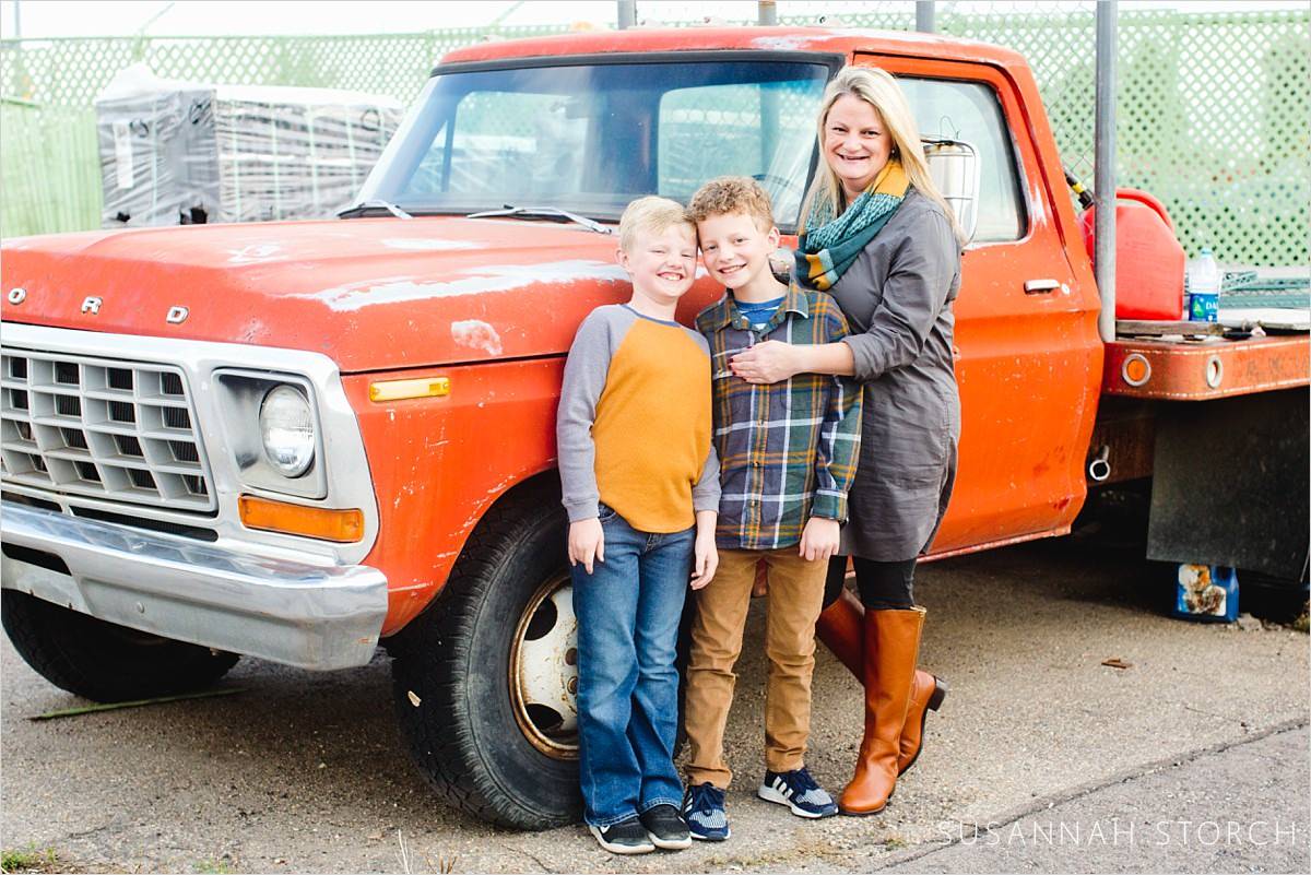 mom and her sons stand by an old pick up truck