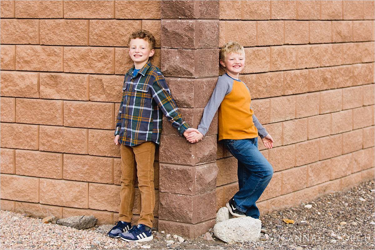brothers hold hands around a wall