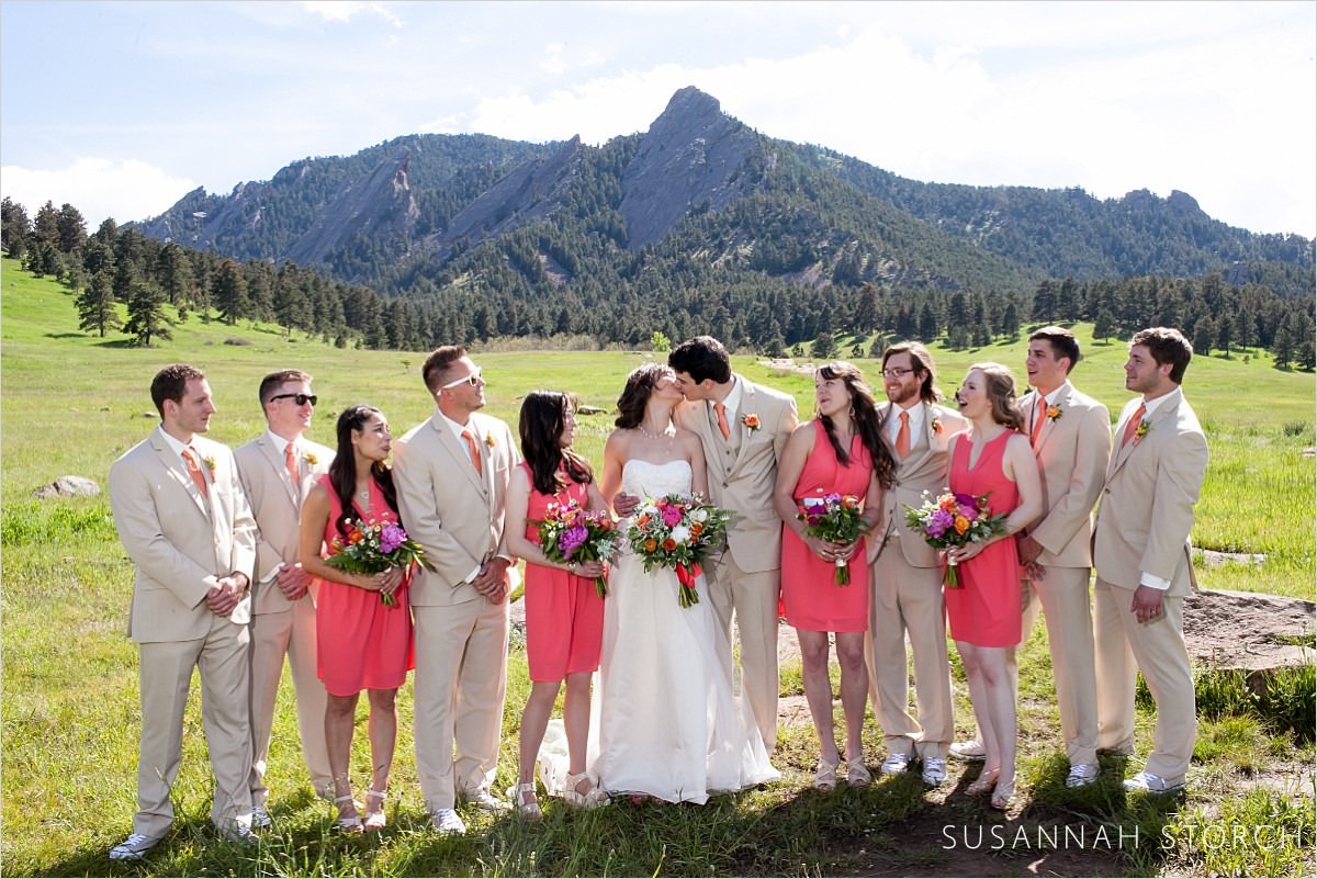 bridesmaids in pink and groomsmen in tan stand in front of the mountains