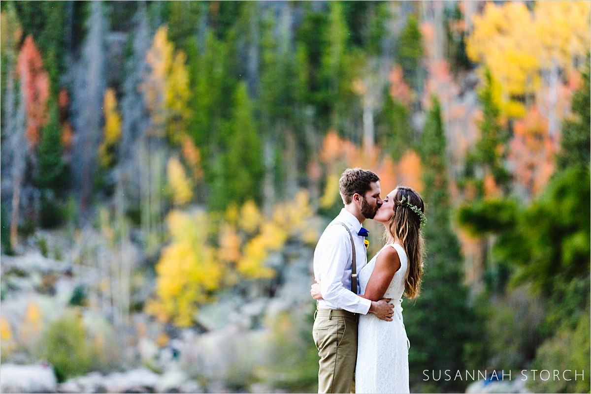 wedding couple kiss in front of fall foliage in rocky mountain national park