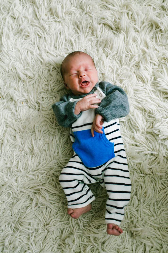 a baby boy in a cute outfit on a white shag rug
