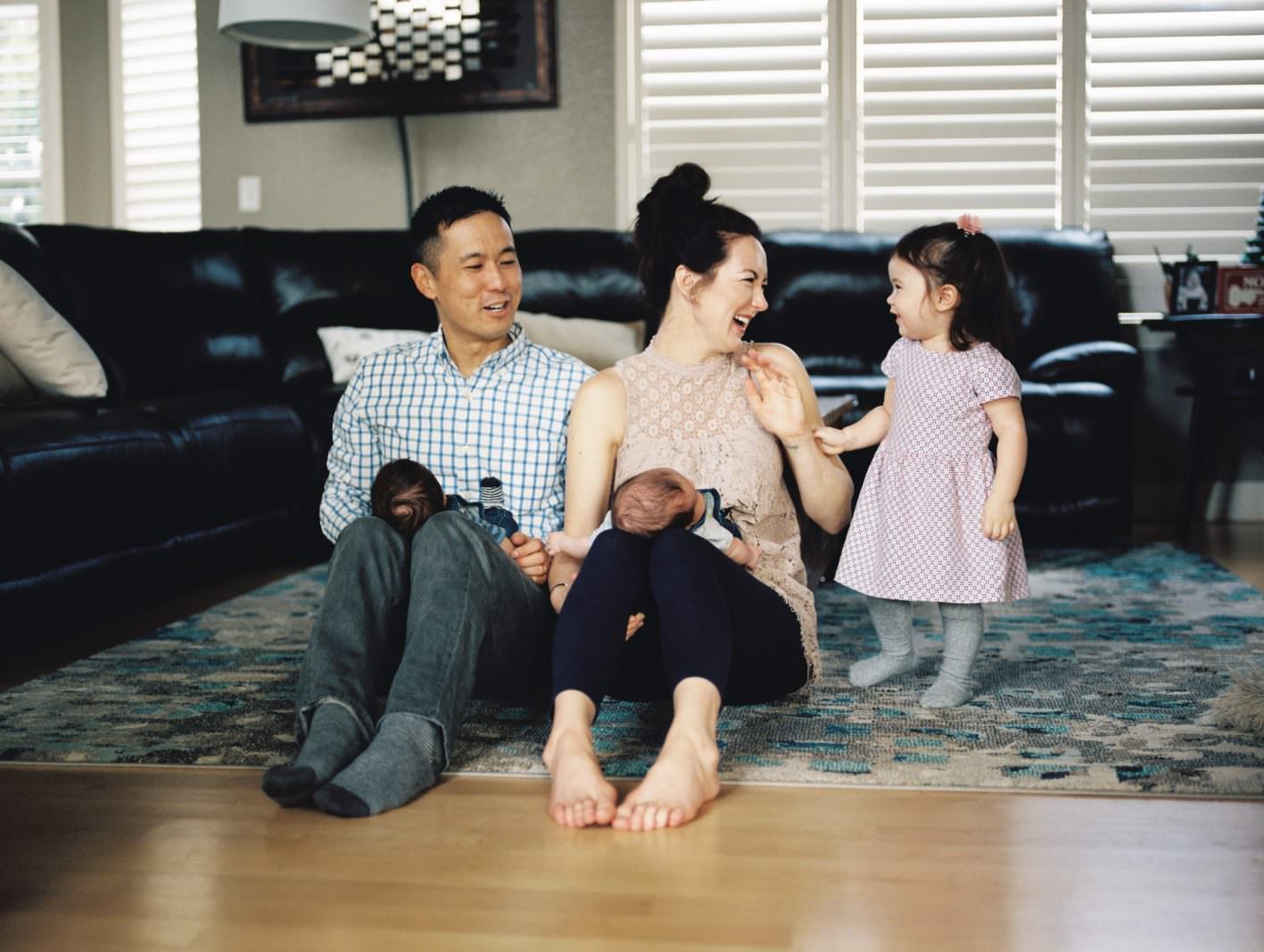 a mom, dad, toddler, and babies laugh