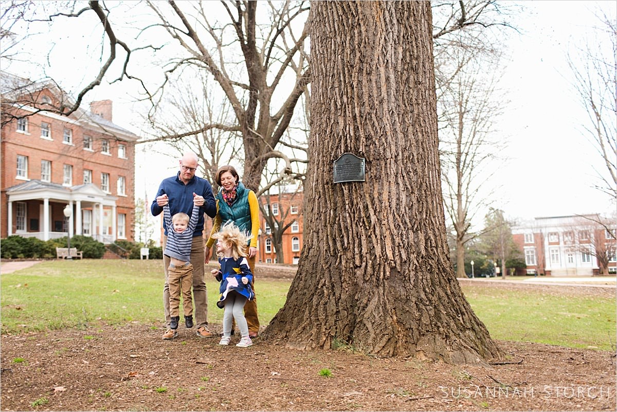 a family stands by a big tree