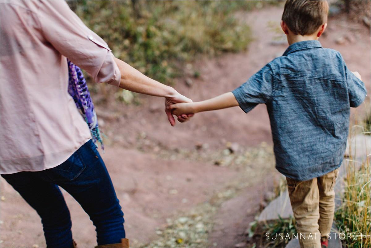 mom and son holding hands while hiking down a hill