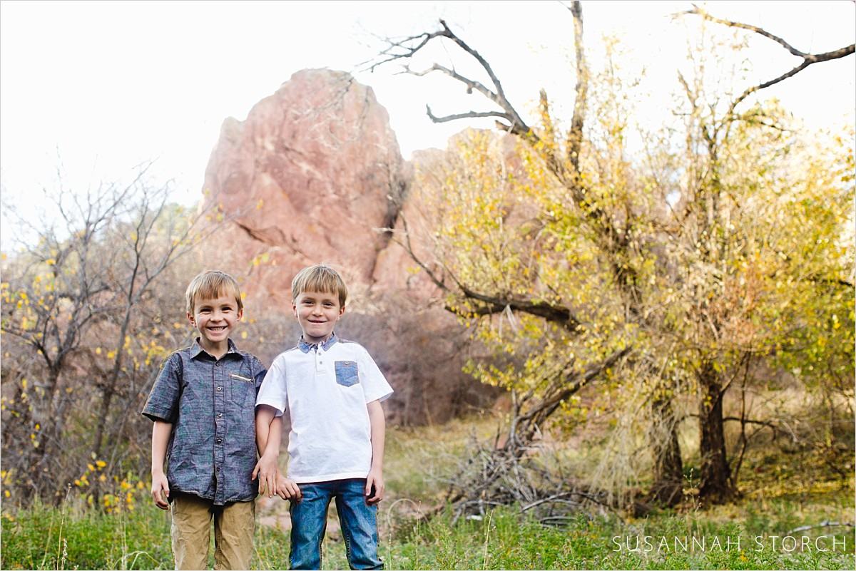 twin boys stand in front of rocks at settler's park in boulder