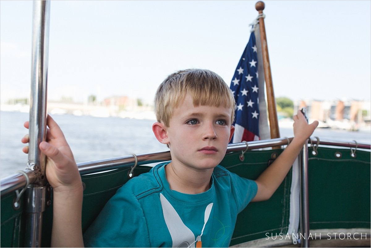 boy sits at the front of a boat