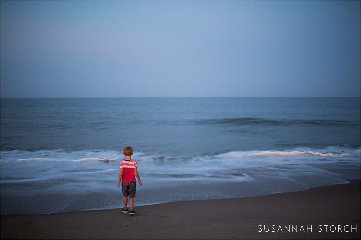 boy looks out on ocean at dusk