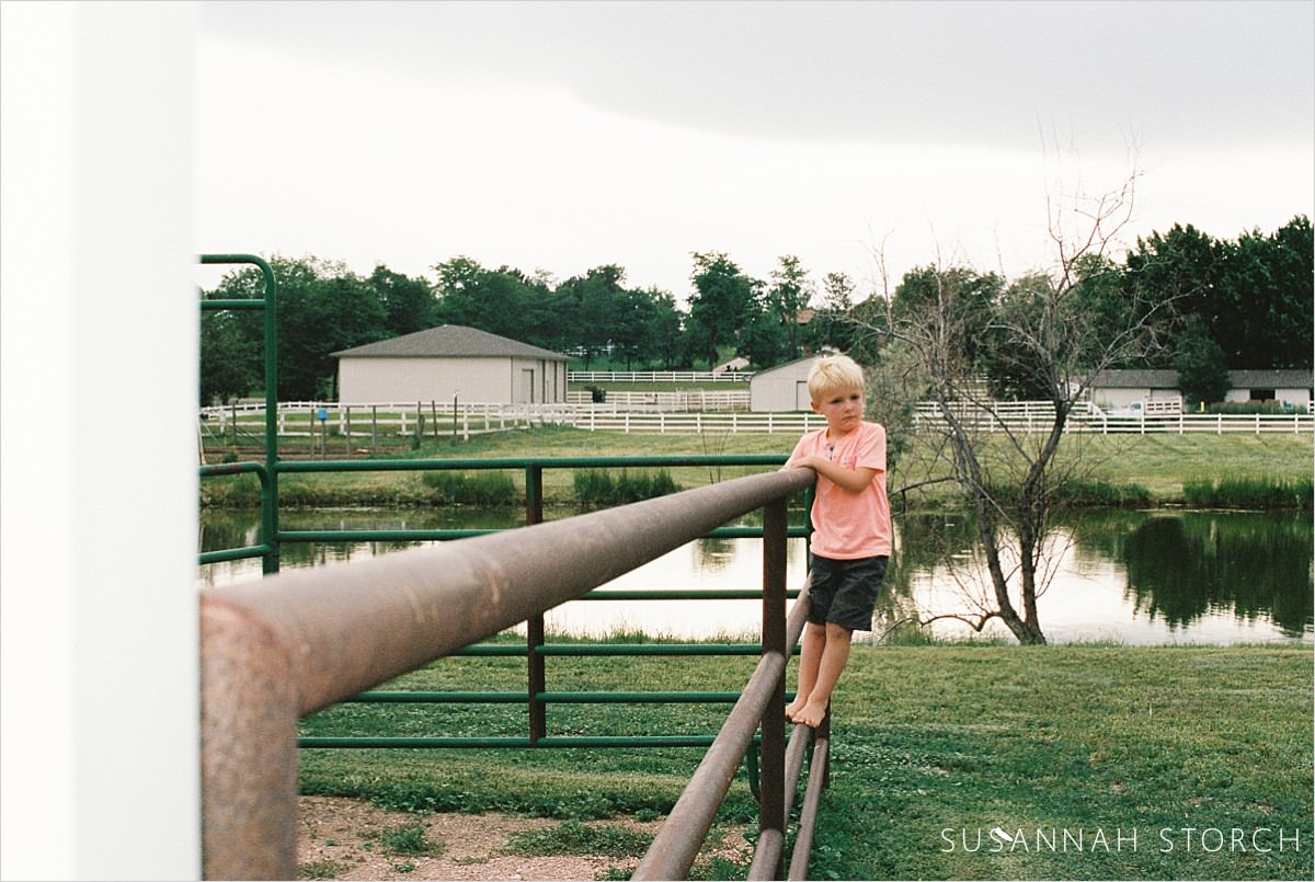 colorado boy stands on a barn fence