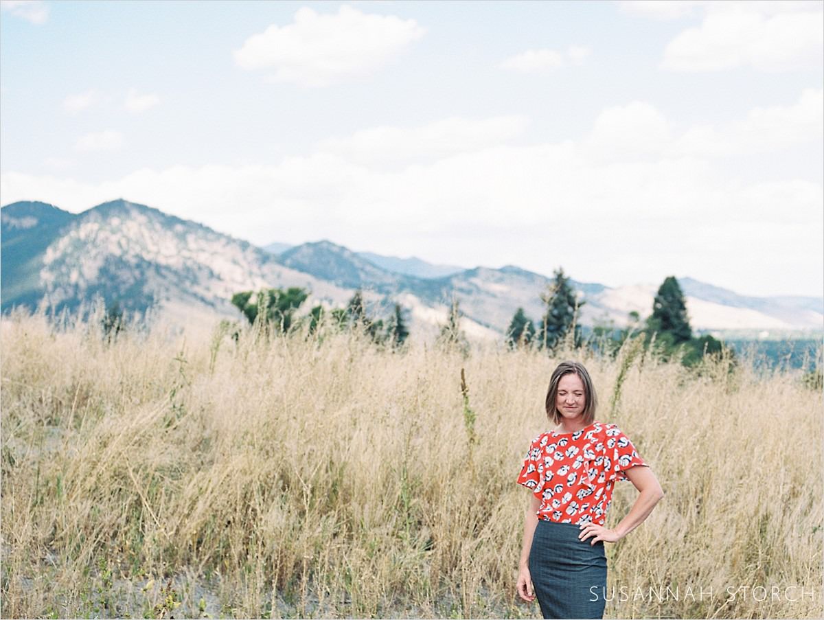 woman stands in tall grass in mountains