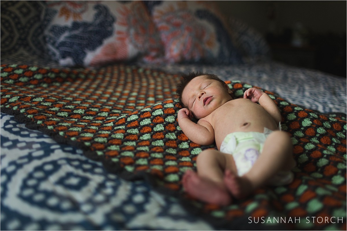 newborn baby lies on blanket with feet in air