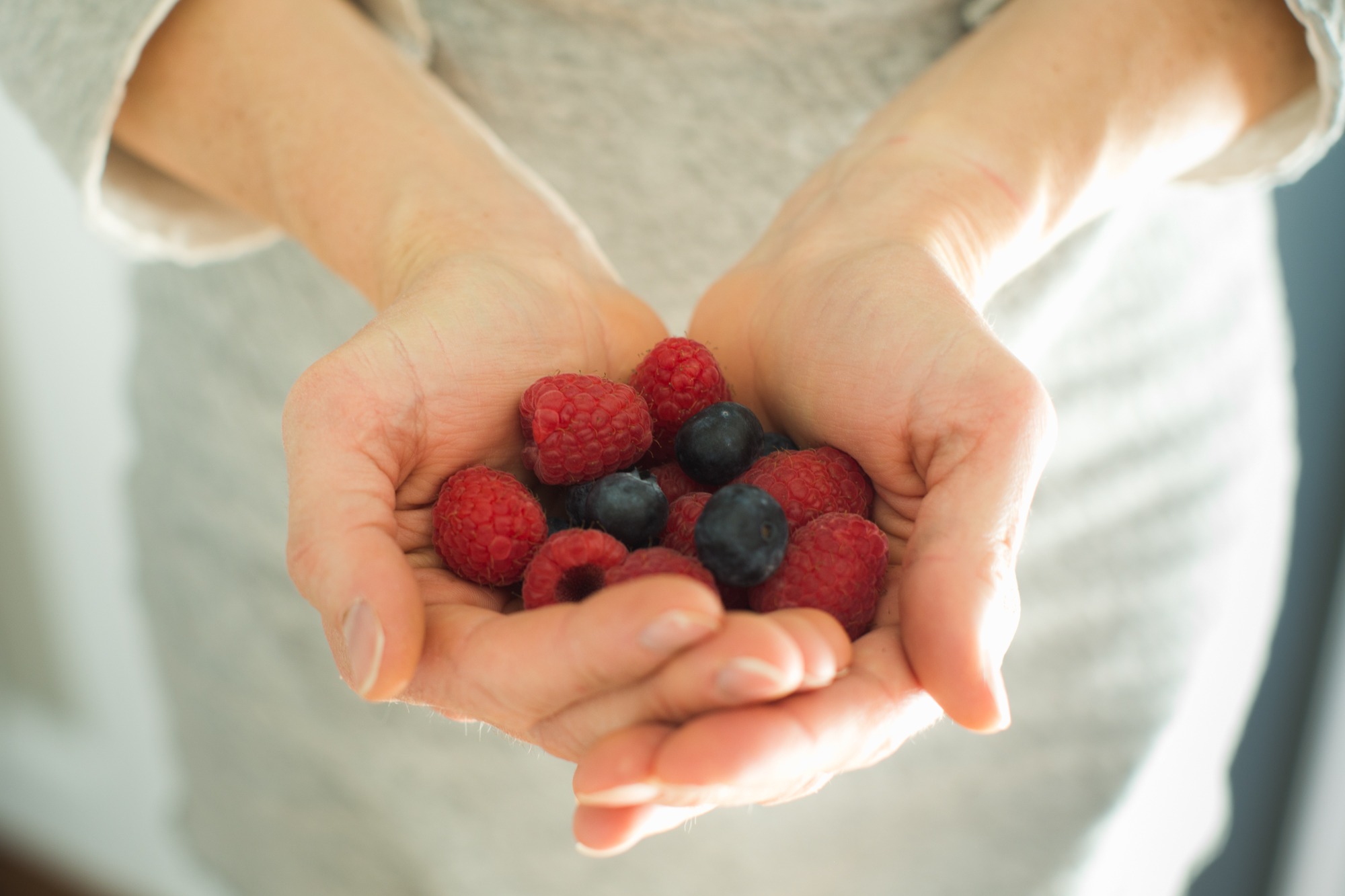 woman's hands hold raspberries