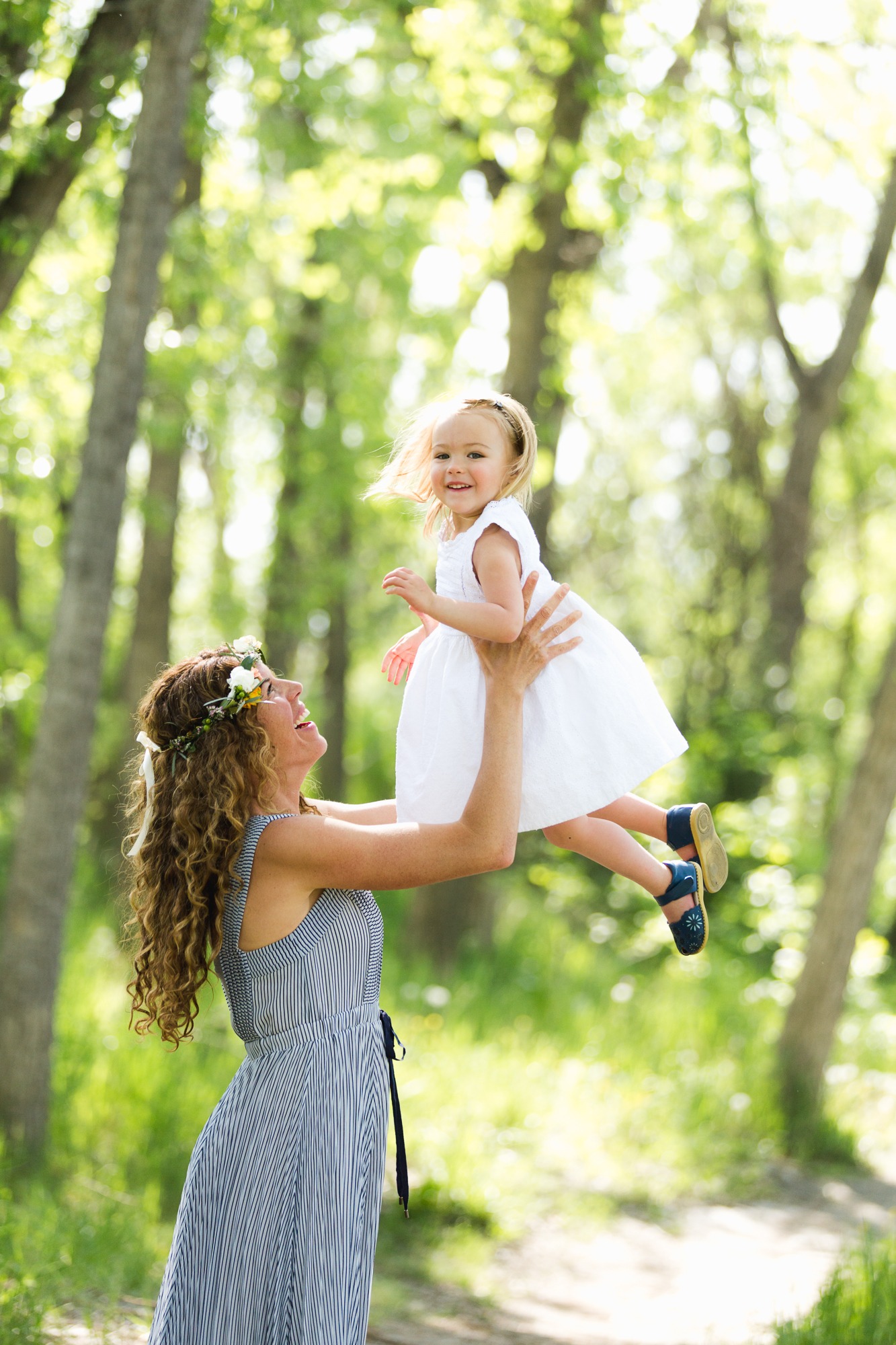 mom lifts young daughter up into the air