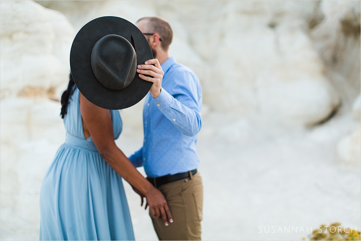 couple kiss behind hat