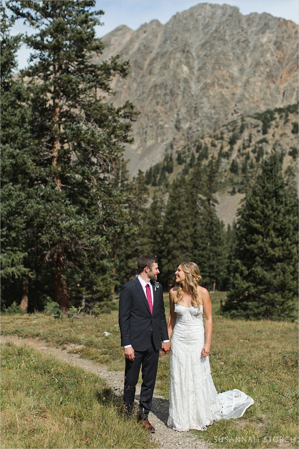 a couple look at each other by rugged mountain peaks