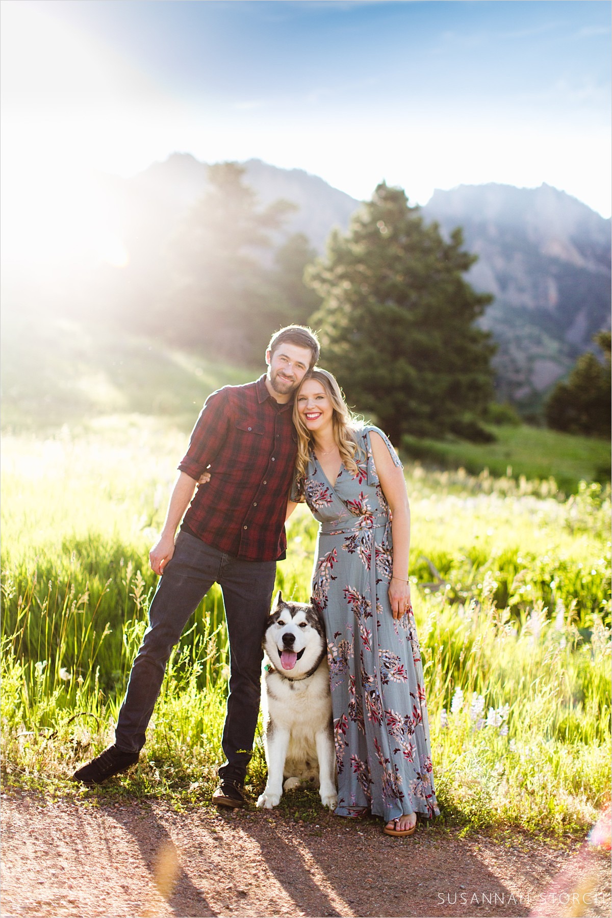 a couple pose in beautiful light with their handsome dog
