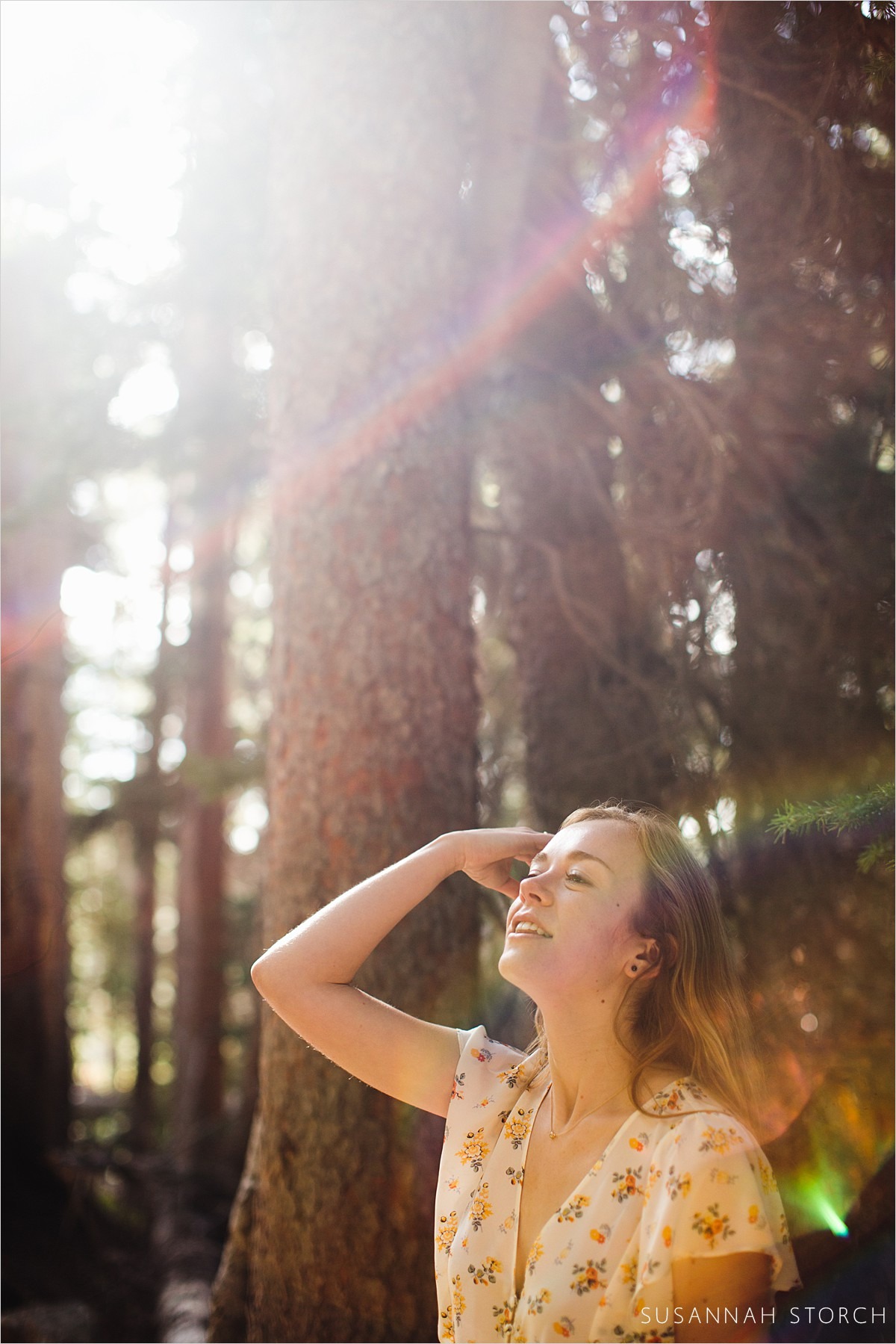 a woman looks up while combing back her hair in a forest