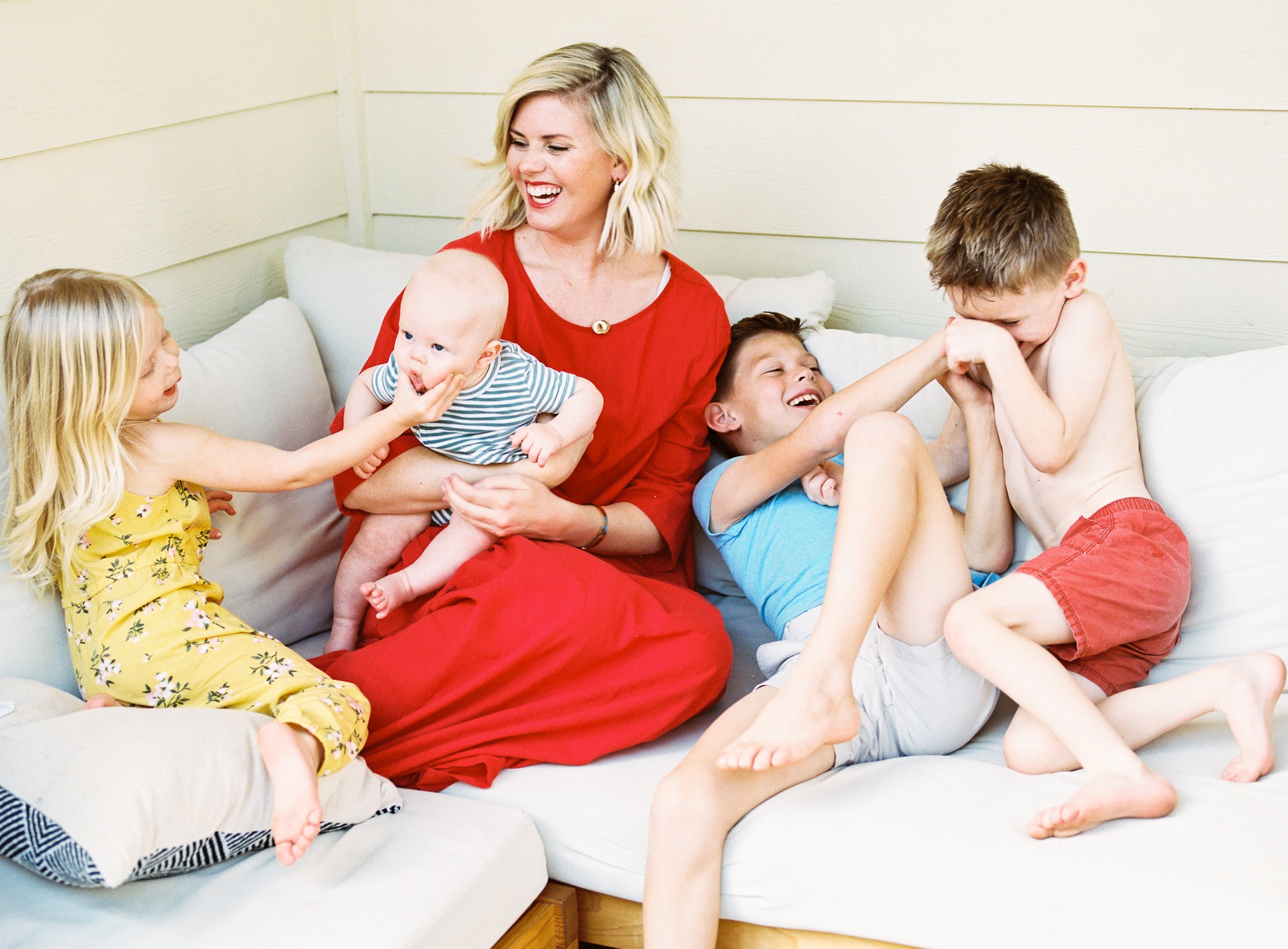 mom in red sits on couch with her four kids