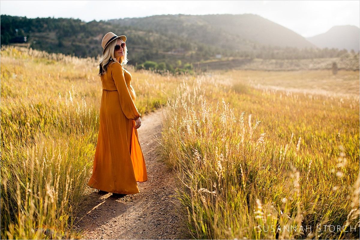 pregnant woman in orange walks in tall grasses