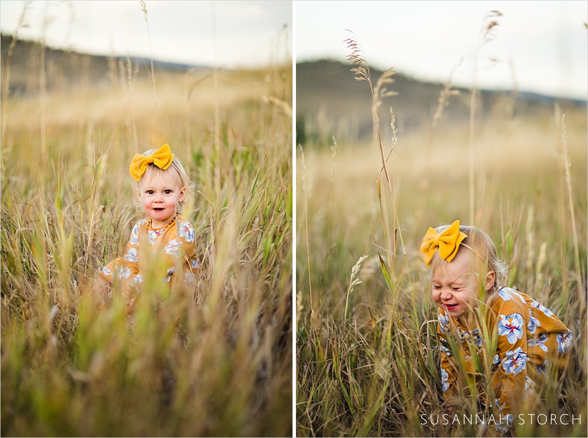 toddler girl sits happily in tall grass