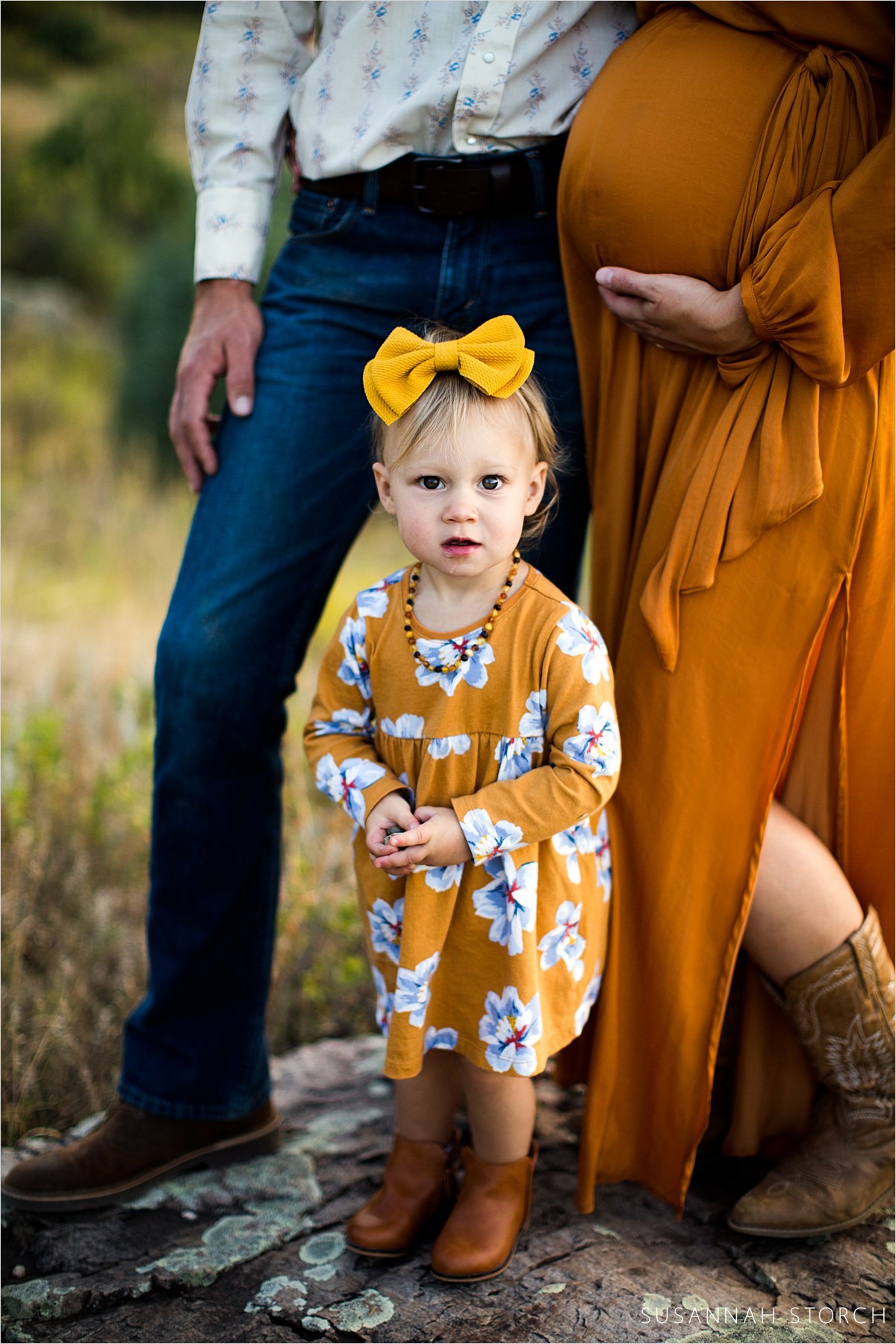 toddler girl poses in front of parents