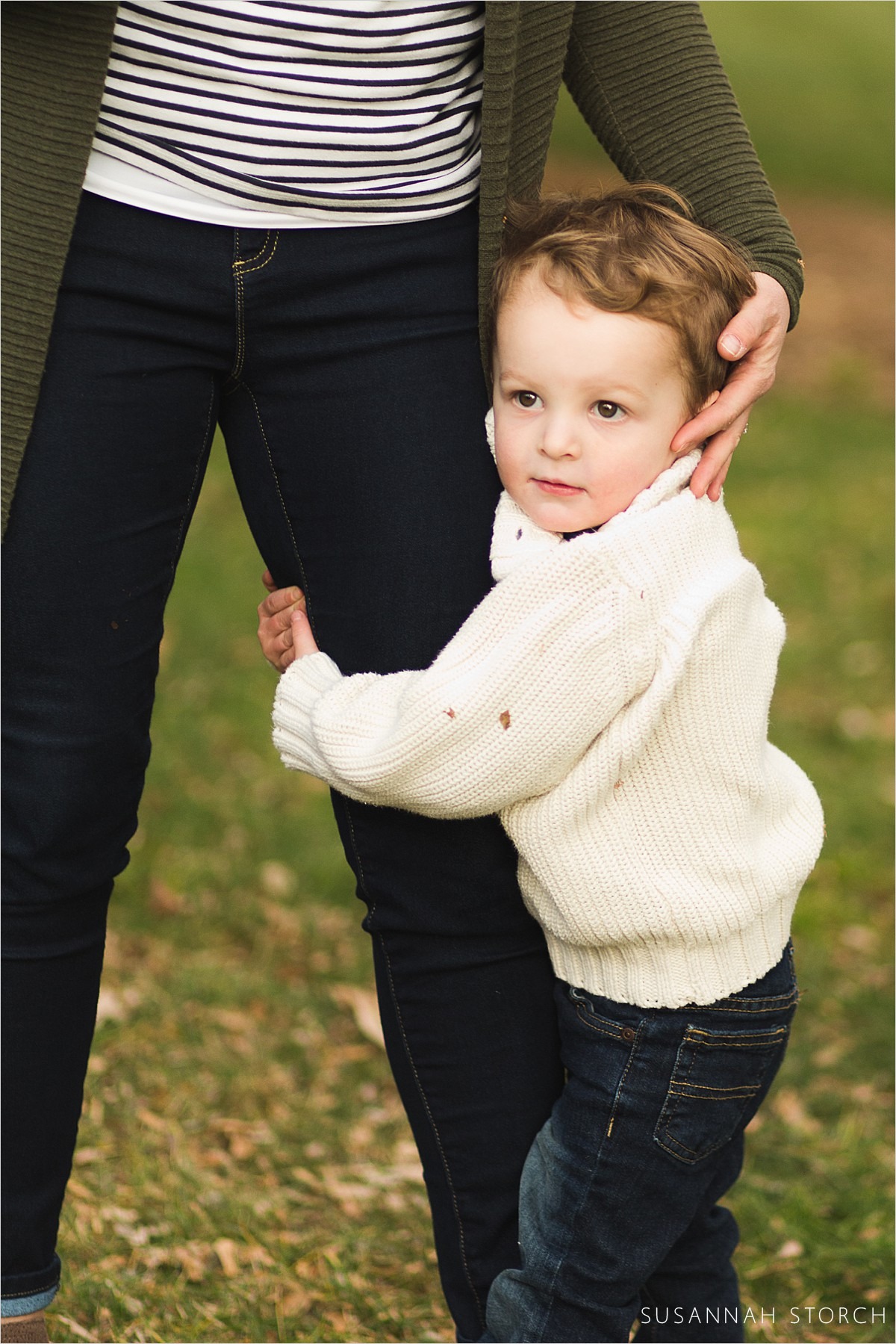 toddler outdoor photoshoot with boy hugging mom's leg