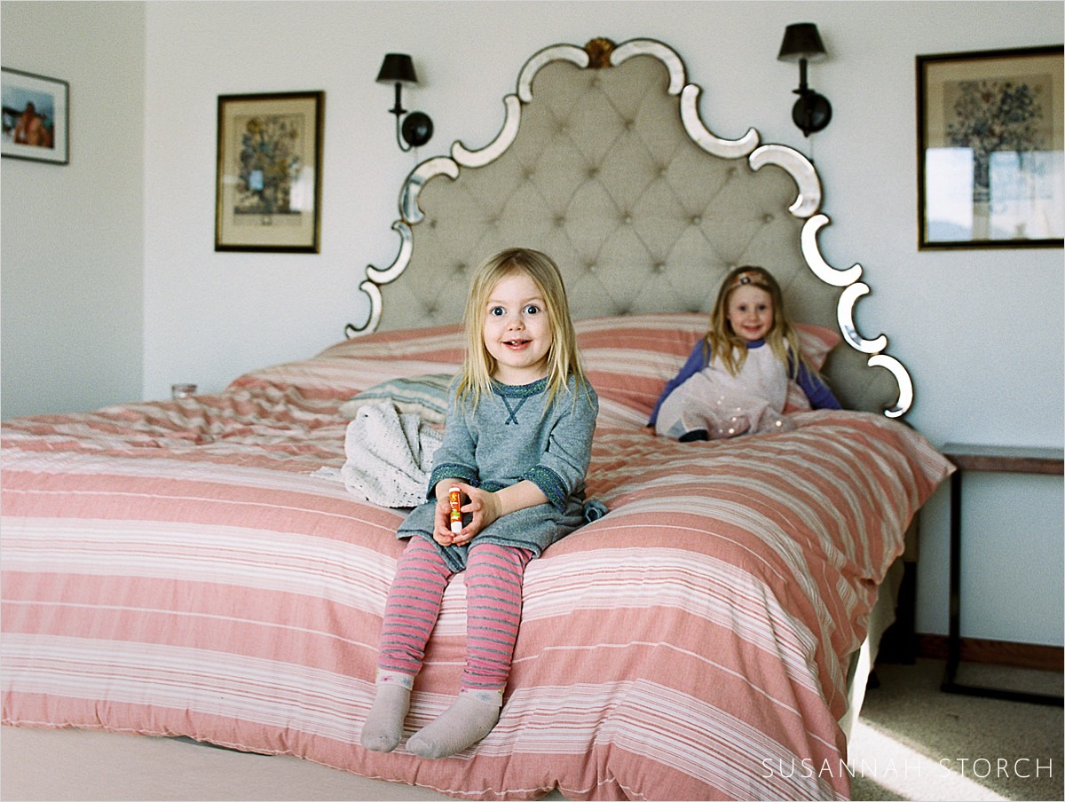 sisters sit on a pink bed