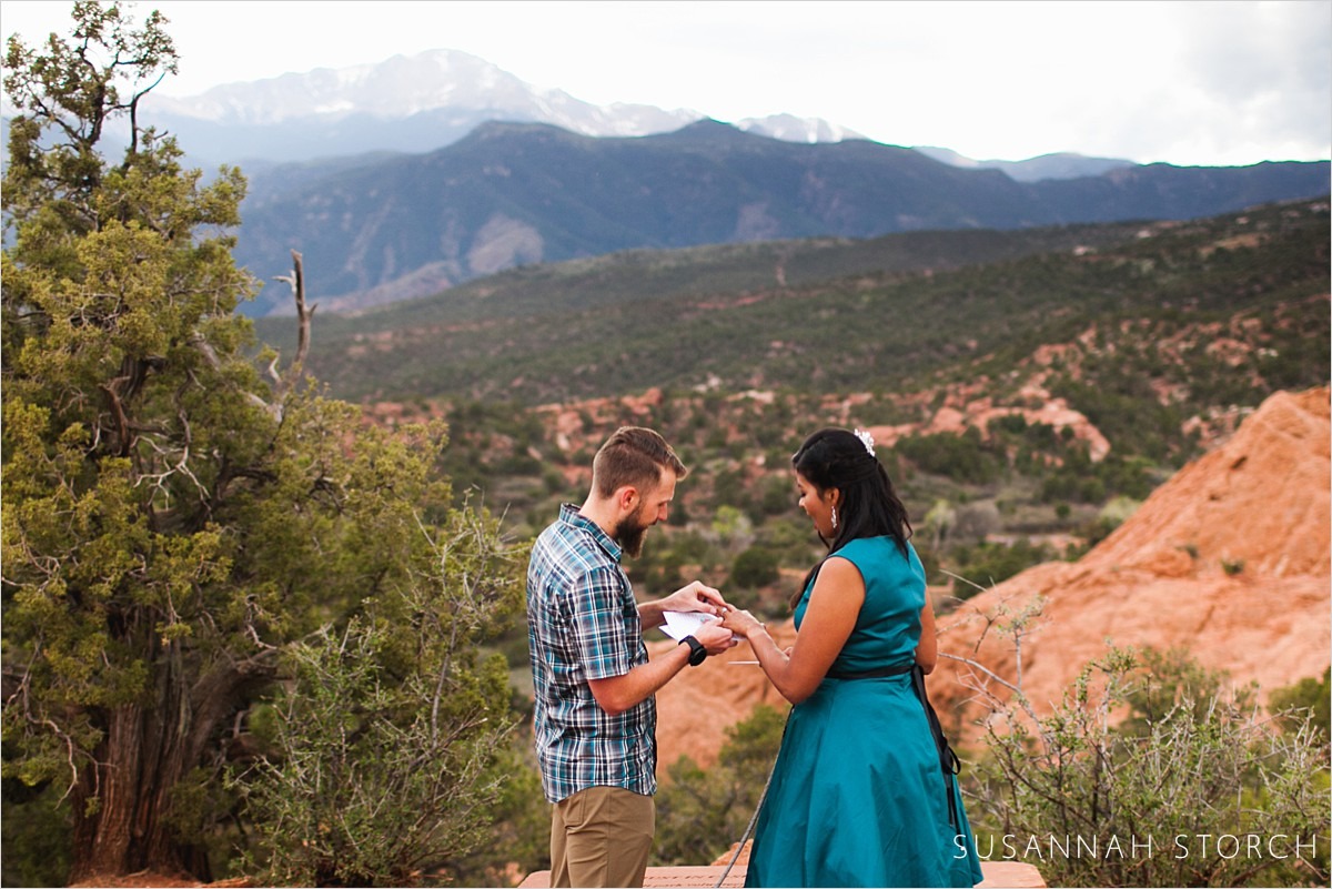 a couple exchange rings during their elopement in front of gorgeous mountains