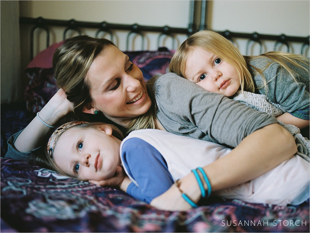 a mom snuggles with her daughters