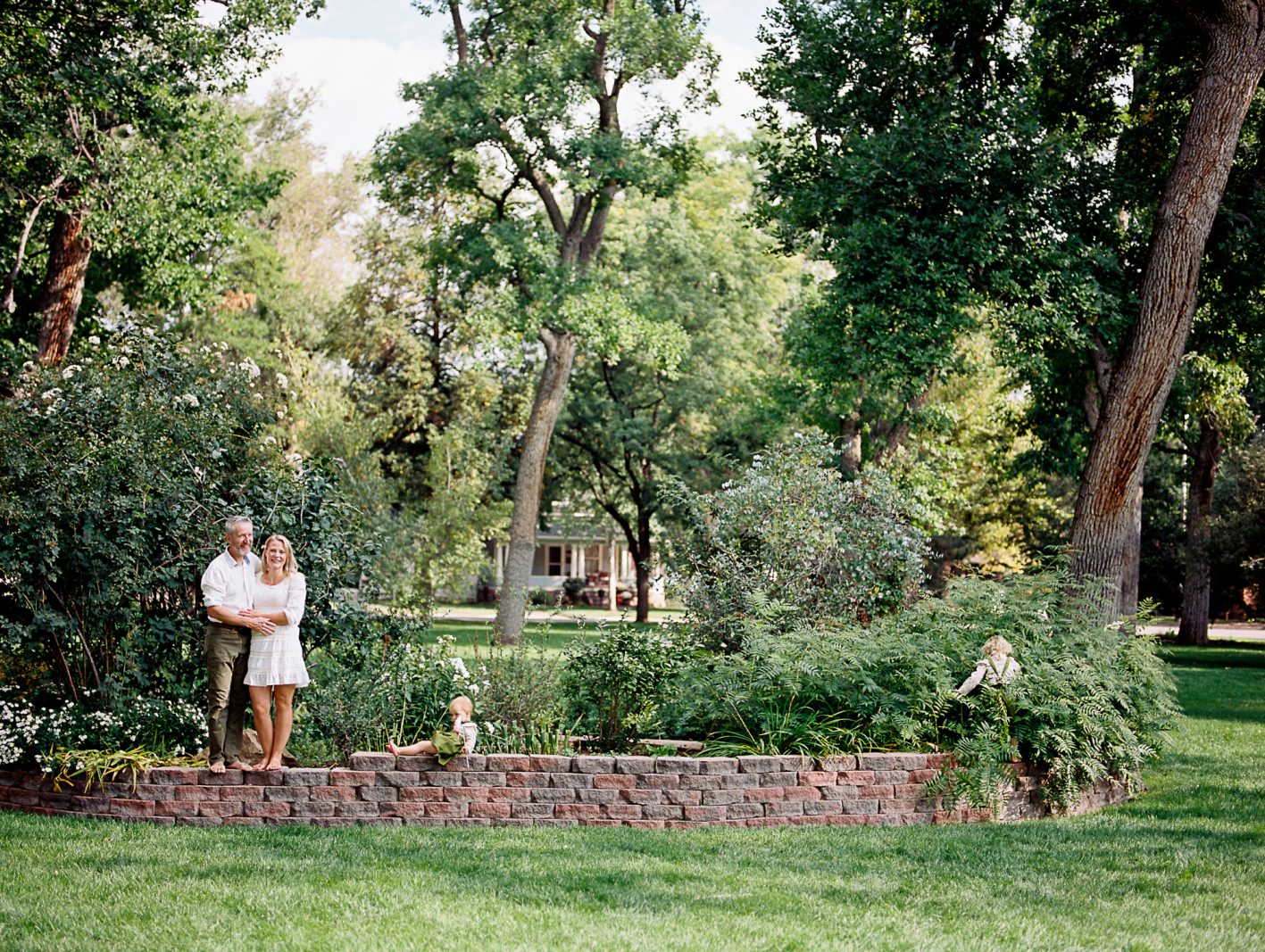 family stands and walks on small brick wall