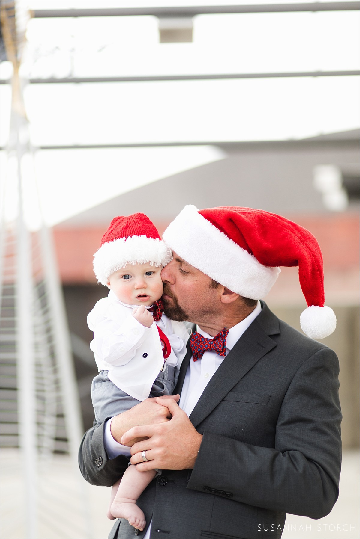 dad in santa hat kisses baby son