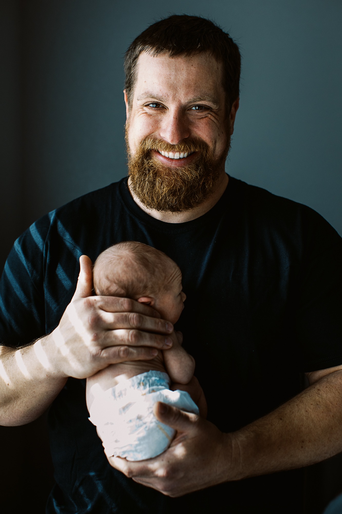 dad looks at camera while holding newborn baby boy