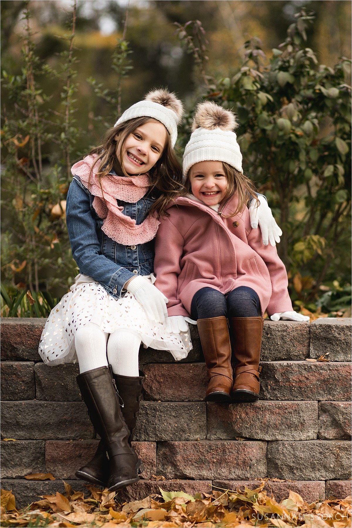 sisters sit on a brick wall during a fall family session