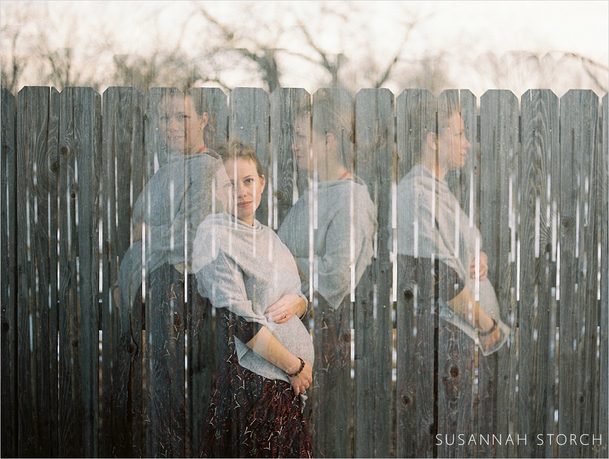 quadruple exposure of a pregnant woman with a gray scarf standing in front of a wood fence