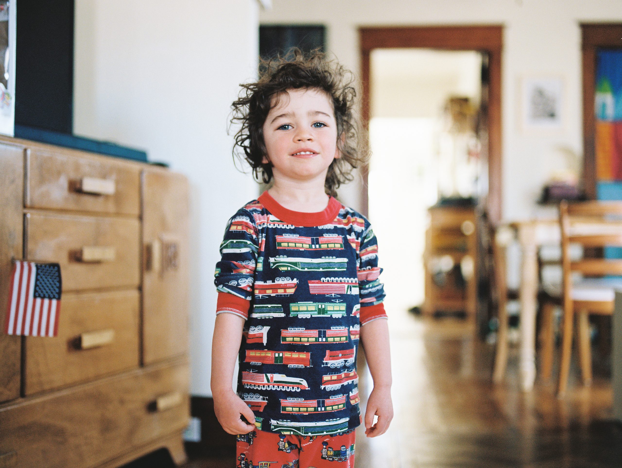 boy with curly hair stands in his living room