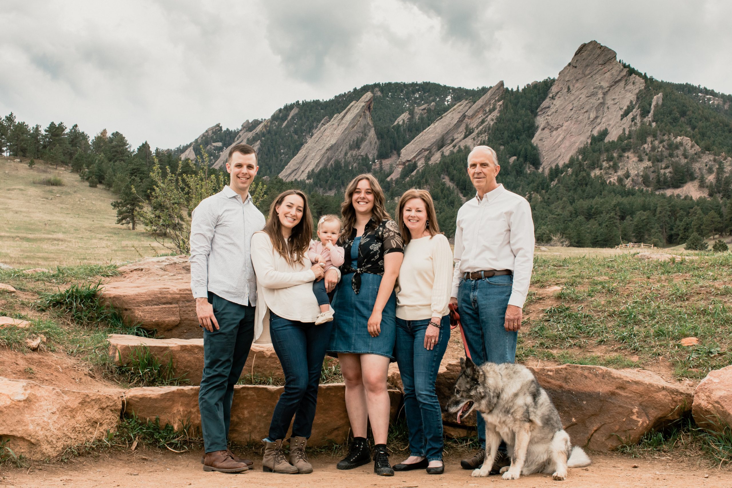 family with baby girl and dog stand in front of boulder's flatirons