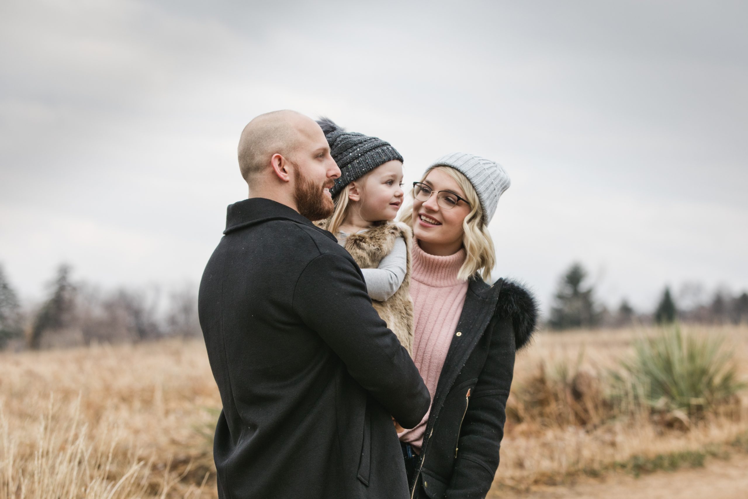 mom looks at daughter while dad hold her on a winter day