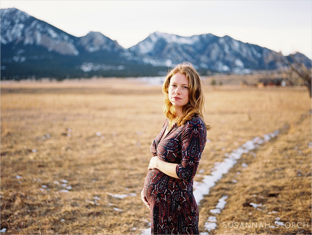 pregnant woman holds belly in front of boulder, co mountains