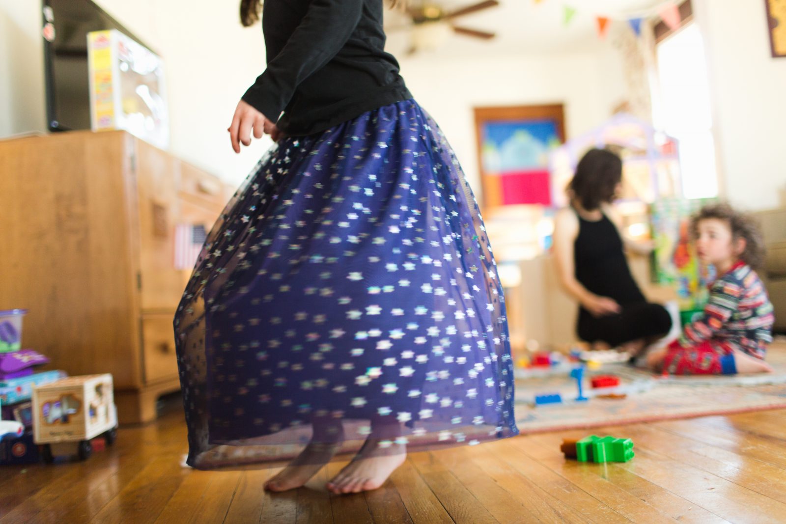 girl in purple skirt twirls in her living room