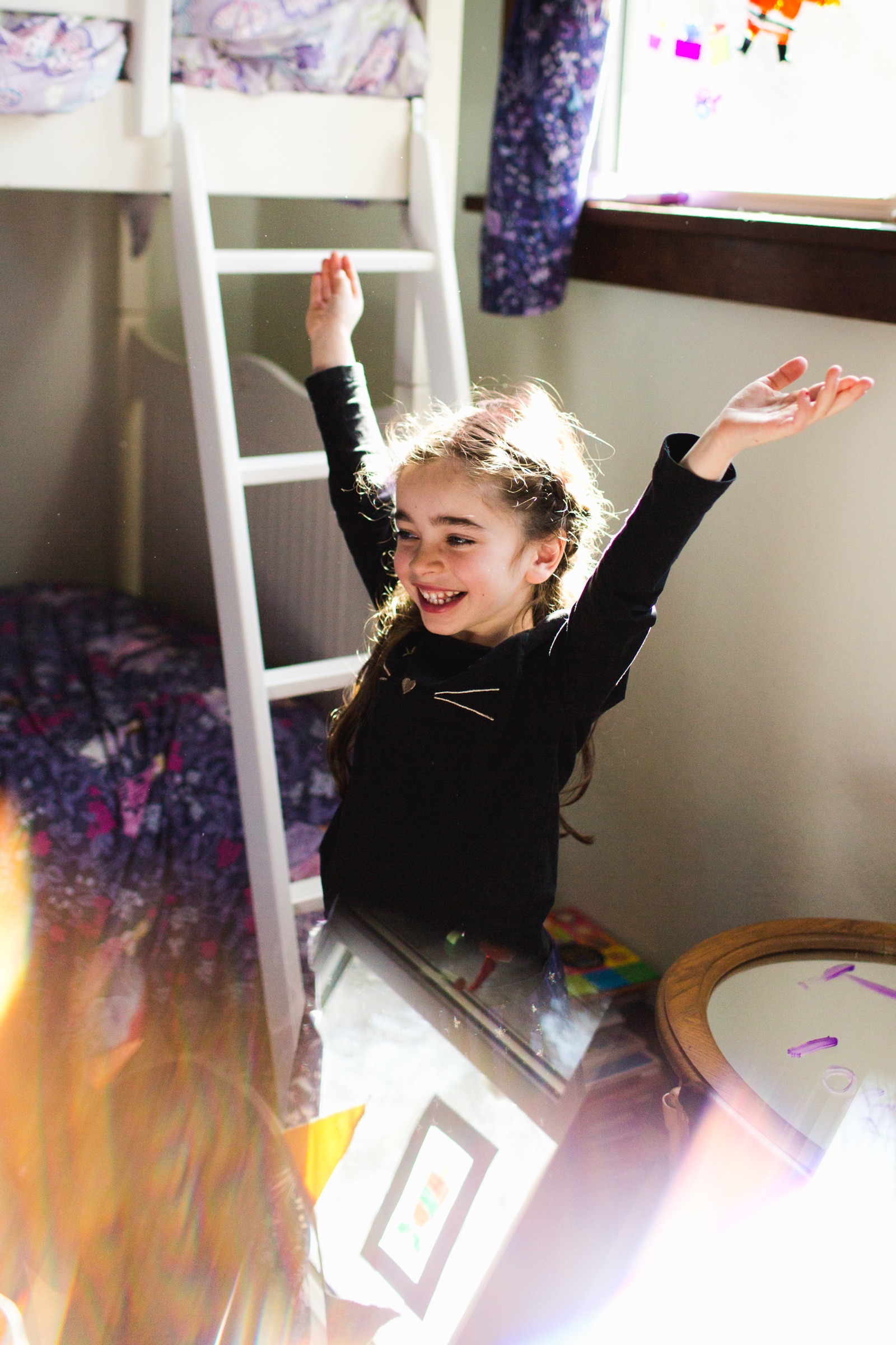 ta da! girl throws hands in air during an in home family session