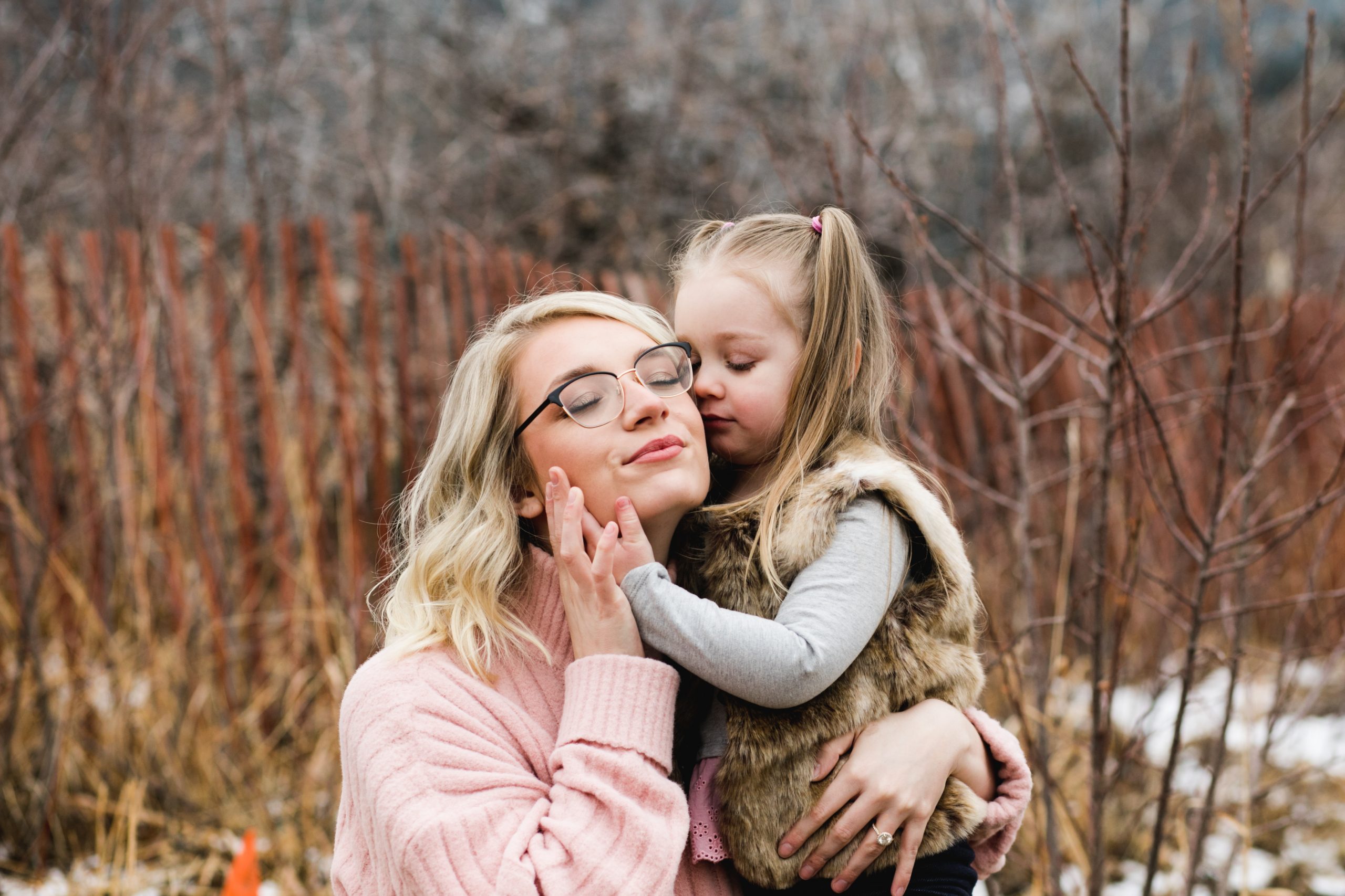 Daughter snuggles into her mama's face during an outdoor winter photo session