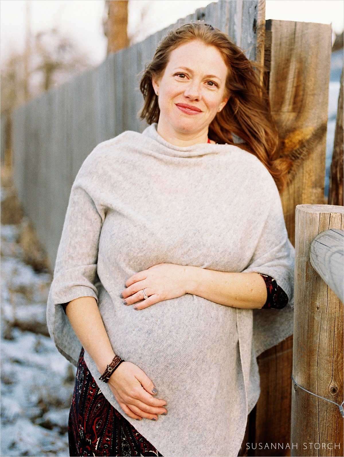pregnant woman with gray shawl and red hair smiles