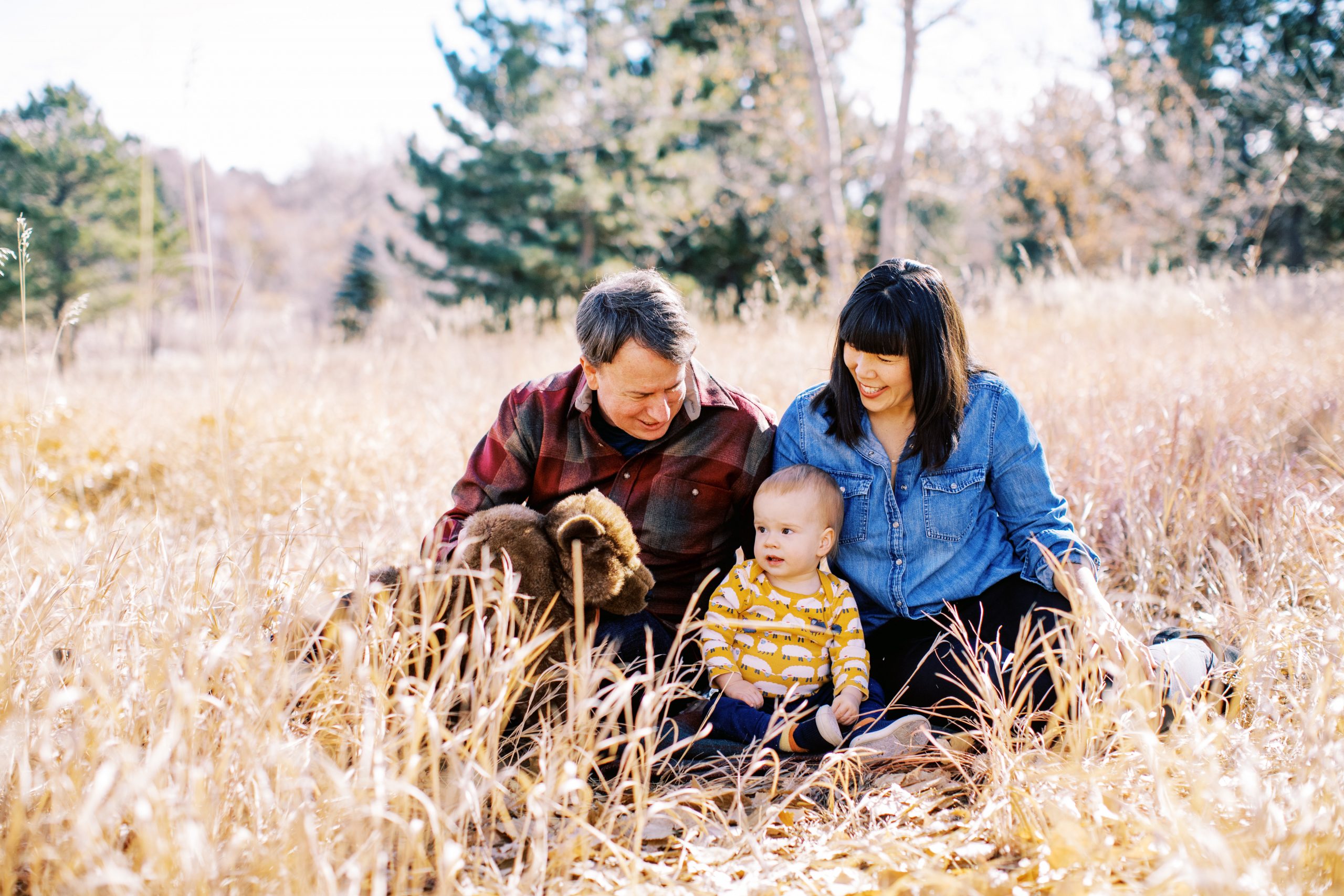 family of three sit in colorado grass
