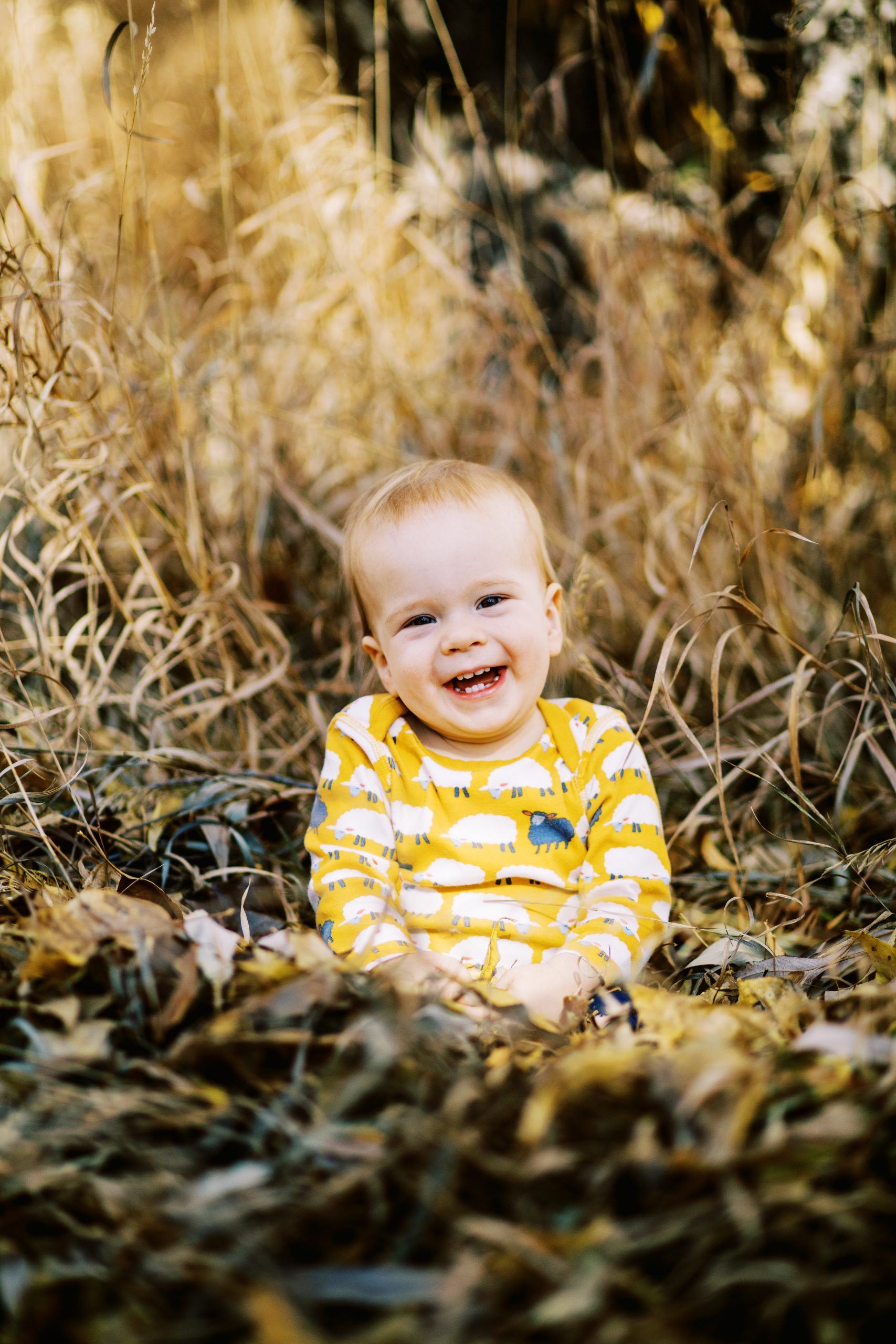 smiling baby sitting in fall leaves