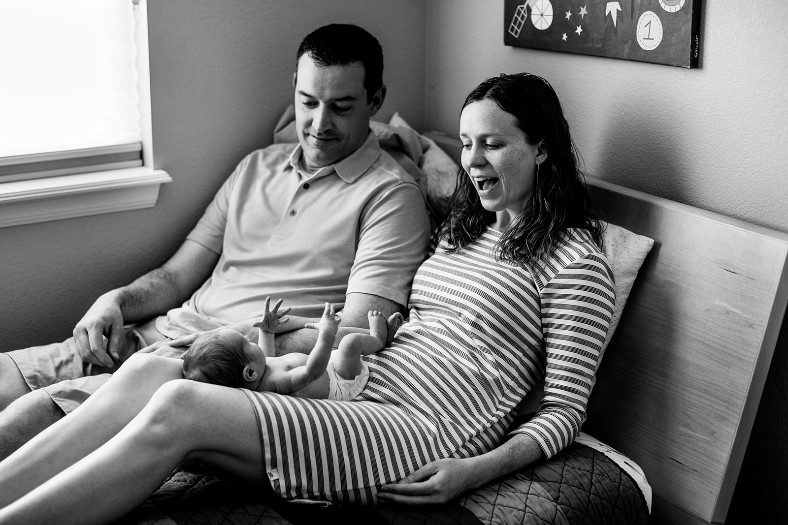 black and white photo of parents and a newborn baby boy who lies on mom's legs