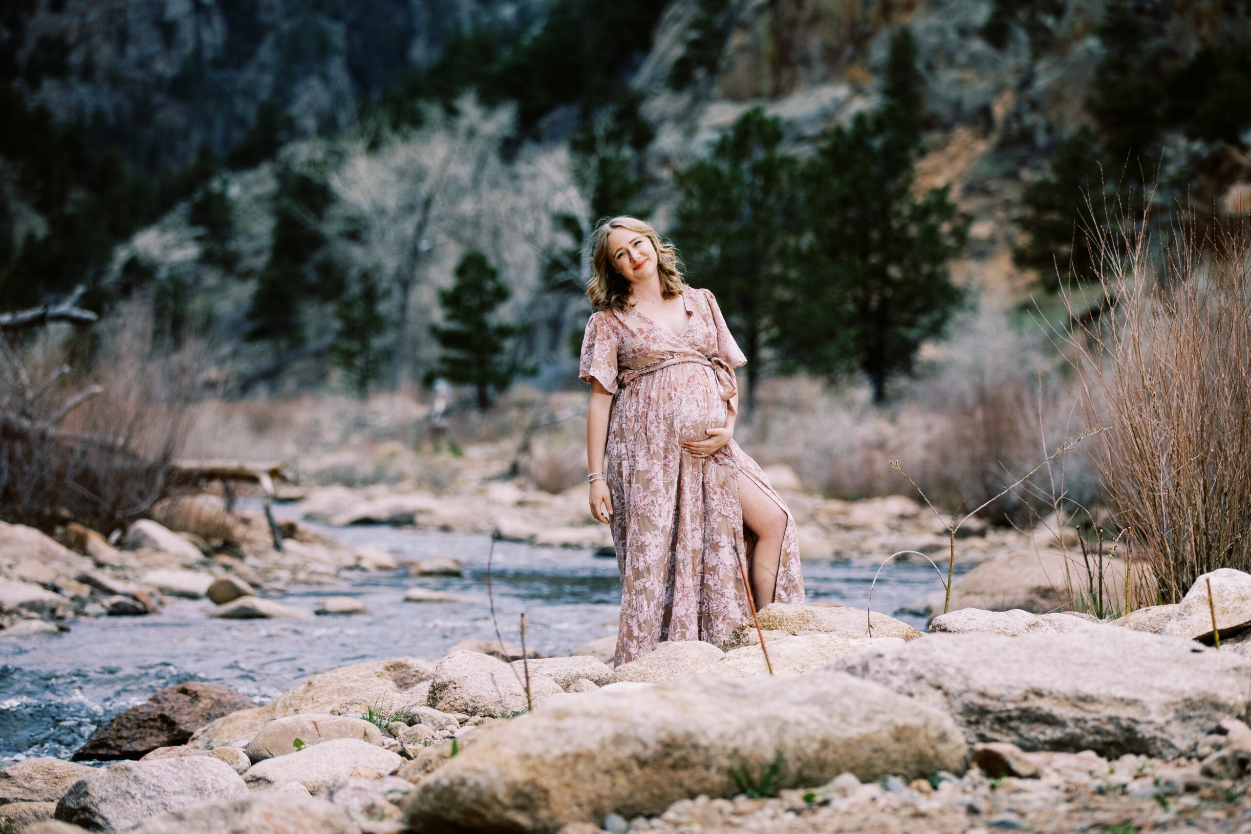 pregnant woman stands in front of river