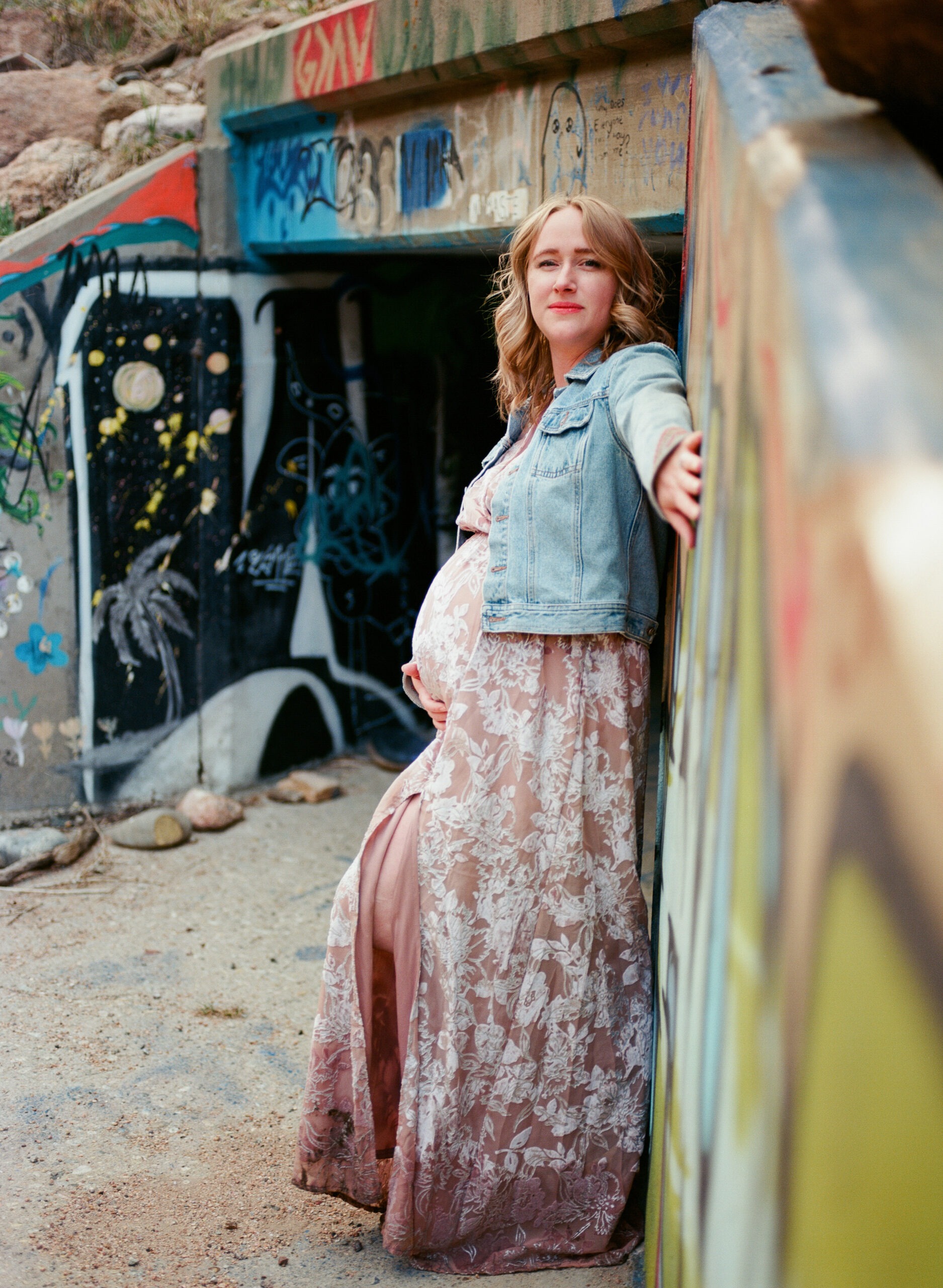 woman stands by road tunnel for maternity photo session