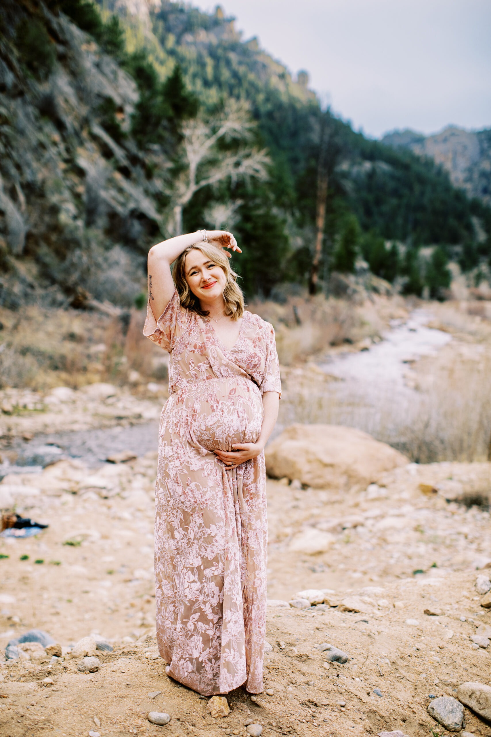 a pregnant woman poses in front of a colorado river